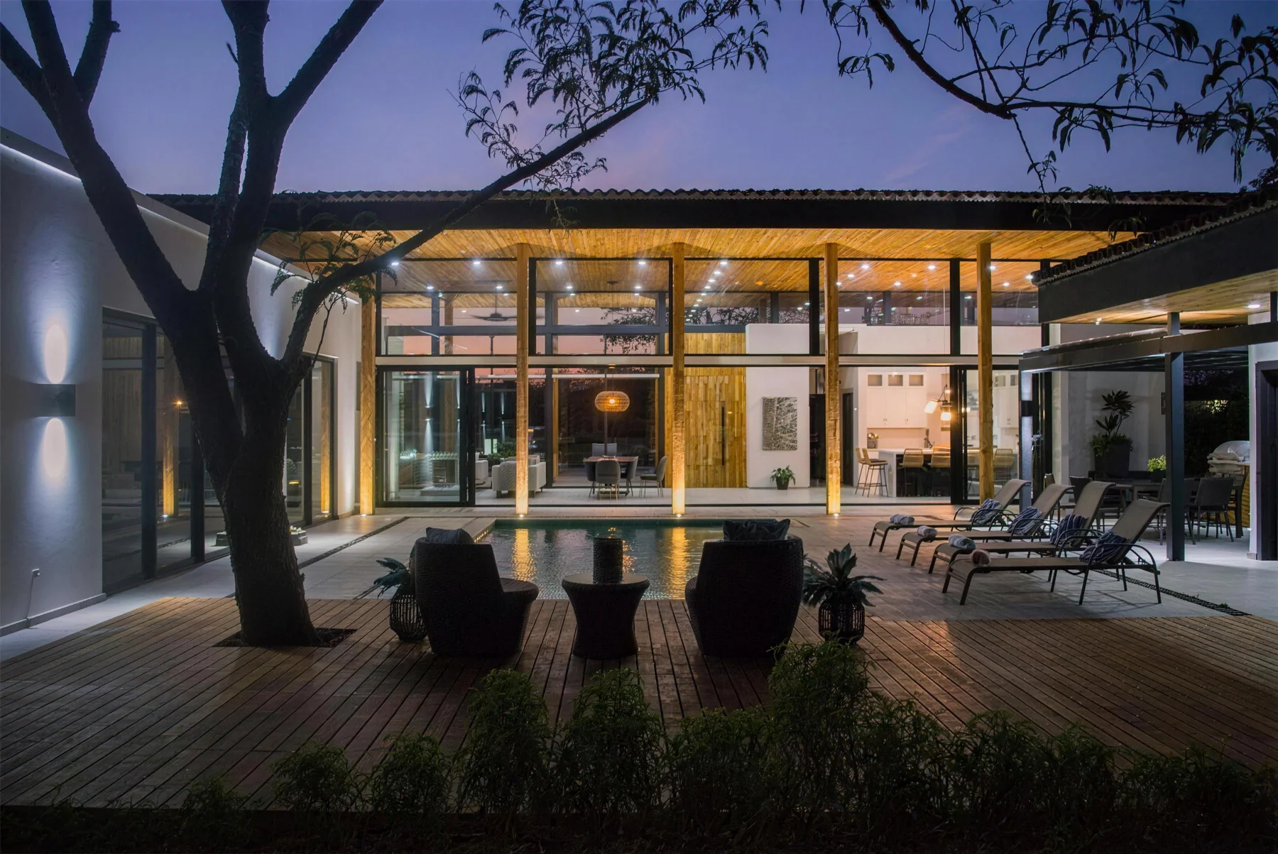 Las Brisas 30 at dusk, with warm interiors opening to the pool and timber deck