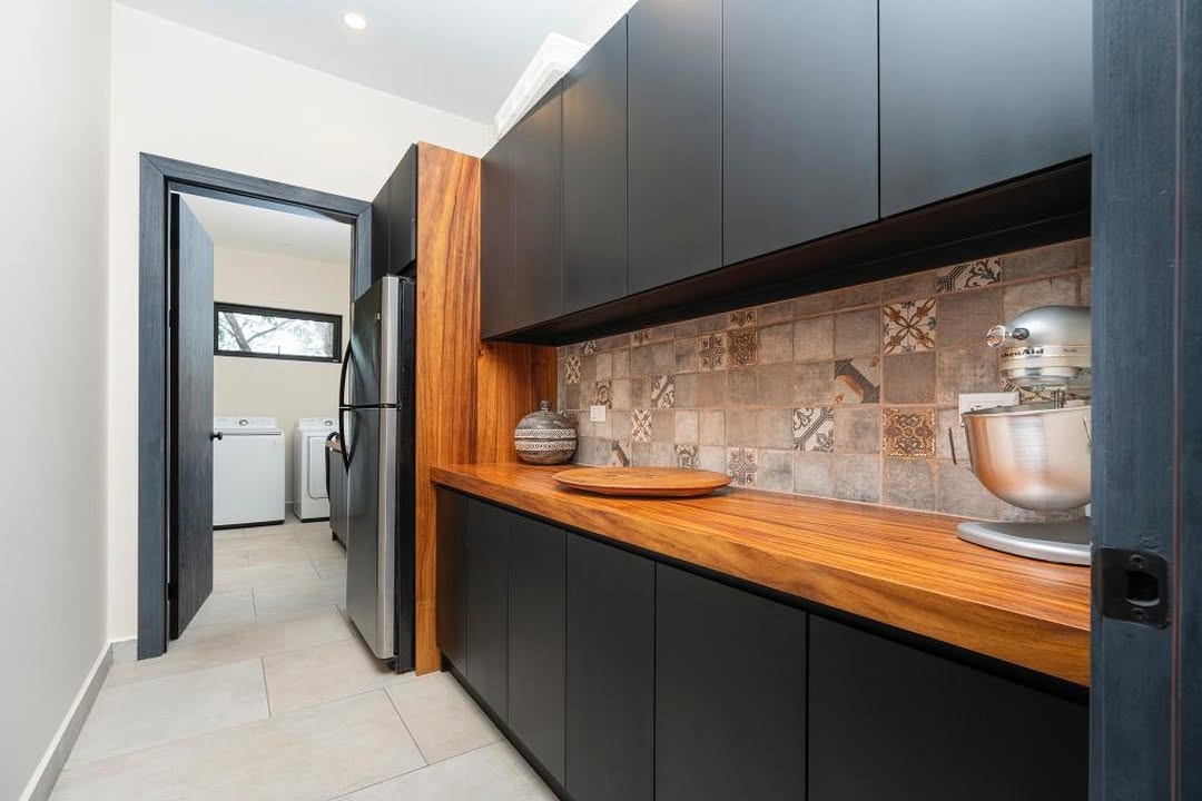 Pantry with dark cabinetry, a timber counter, and patterned tile